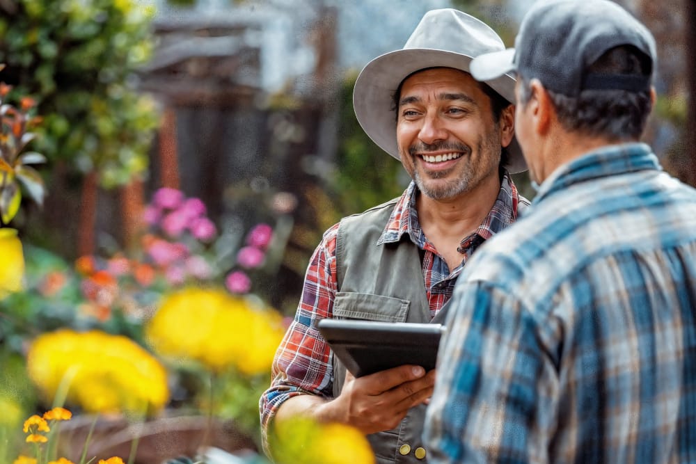 A homeowner consulting with an experienced Oakville landscaping contractor holding a tablet in a colorful garden.